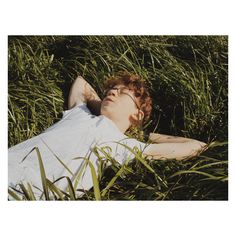 a man laying in the grass with his eyes closed