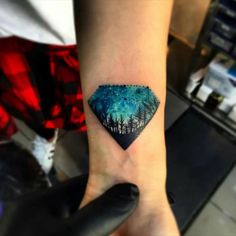 a person's arm with a small tattoo on the wrist and trees in the background