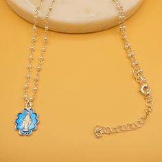 Embrace faith and elegance with this stunning Miraculous Medal necklace. Crafted in Italy, this exquisite piece features a silver medal adorned with vibrant blue enamel, capturing the beauty of the Virgin Mary. The delicate pearl beaded chain adds a touch of sophistication, making it a perfect accessory for everyday wear or special occasions. This necklace is a beautiful reminder of faith and a cherished gift for loved ones. Dimensions & Specifications: Medal size: 13mm x 11mm Materials: Sterling silver, blue enamel, natural freshwater pearls. Made in Italy. Each piece comes packaged in an elegant box. We provide 2-day shipping on deliveries and accept money-back returns for all orders from our shop. Guadalupe Gifts Promise Artwork authenticity. Pay our artisans a reasonable wage to create Silver Jewelry With Miraculous Medal And Round Beads, Silver Miraculous Medal Necklace With Round Beads, Blue Beaded Chain Charm Necklace As Gift, Silver Pendant Charm Necklace With Beaded Chain, Miraculous Medal Necklace, Catholic Necklace, Catholic Jewelry, Italian Jewelry, Miraculous Medal