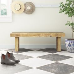 a potted plant sitting on top of a checkered floor next to a wooden bench