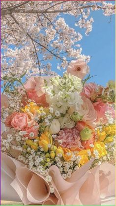 a bouquet of flowers sitting on top of a white cloth covered table with blue sky in the background