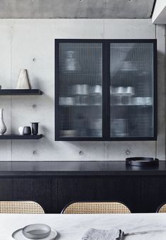 a dining room table with plates and cups on it, next to a wall mounted cabinet