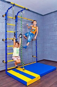 two children are playing on a trampoline in a room with blue walls and wooden floors