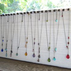 a bunch of necklaces are hanging on a white brick wall in front of a window