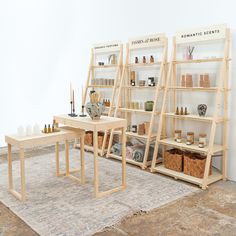 three wooden shelves with bottles and vases on them in front of a white wall