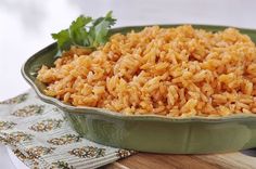 a green bowl filled with rice and garnished with parsley on a wooden cutting board