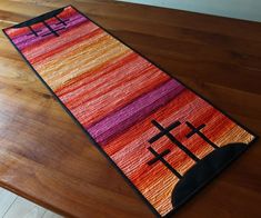 a colorful rug with crosses on it sitting on top of a wooden table