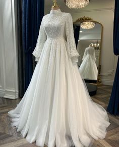 a white wedding dress on display in front of a mirror with blue curtains and chandelier