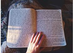 a person's hand resting on an open book with the pages written in cursive writing