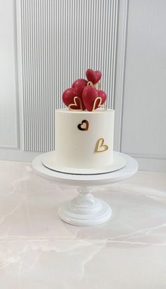 there is a white cake with hearts on the top and gold letters on the bottom