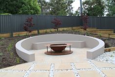 an outdoor fire pit surrounded by landscaping and trees