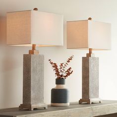 two lamps sitting on top of a table next to a vase with flowers in it