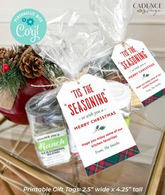 christmas gift tags on a glass table with pine cones and other holiday decorations in the background