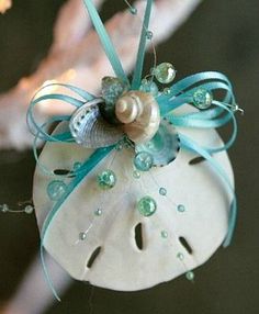 an ornament hanging from a tree branch with pearls and blue ribbons on it