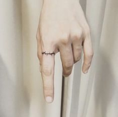 a person's hand with a small tattoo on the middle finger and an arrow in the middle