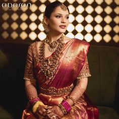 a woman in a red and gold sari sitting on a couch