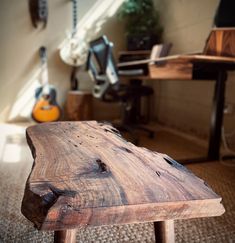 a wooden bench sitting on top of a carpeted floor next to a guitar rack