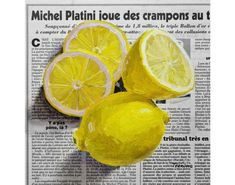 three lemons sitting on top of a newspaper