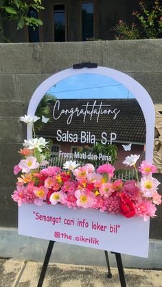 a sign with flowers on it in front of a building