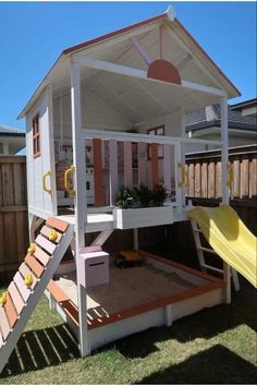 a play house with a slide in the back ground and a yellow slide on top