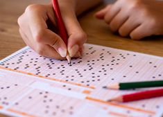 a person is writing on a piece of paper with colored pencils