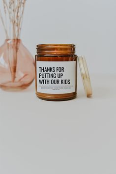 a jar of candles sitting on top of a table next to a vase with flowers