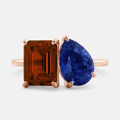 an orange and blue sapphire ring with two pear shaped diamonds on each side, set in rose gold