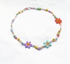 a colorful beaded necklace with flowers and beads on it's end, sitting on a white surface