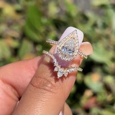 a woman's hand holding a ring with two pear shaped diamonds on top of it