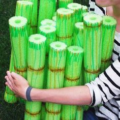 a woman sitting on the grass holding a large stack of green firecrackers