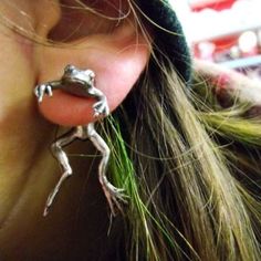 a close up of a person's ear with a frog earrings attached to it