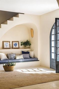 a living room filled with furniture and a large window next to a stair case in front of a doorway