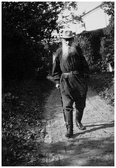 an old man with a long beard walking down a dirt road in the country side