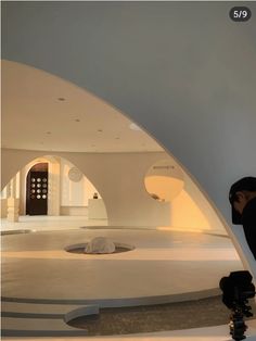 a person is taking a photo in front of a circular room with white walls and flooring