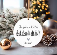 a personalized ornament hanging from a christmas tree with pine cones and ornaments around it