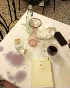 a table topped with glasses and books on top of a white tablecloth covered in water