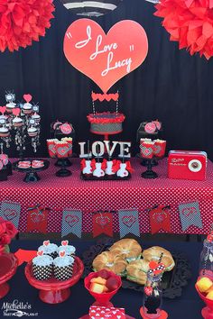 a table topped with cakes and cupcakes next to a heart - shaped balloon