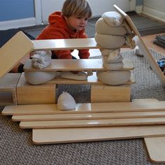 a young boy playing with wooden toys on the floor