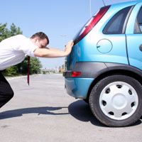 a man is trying to fix his car's tire with the help of a tie