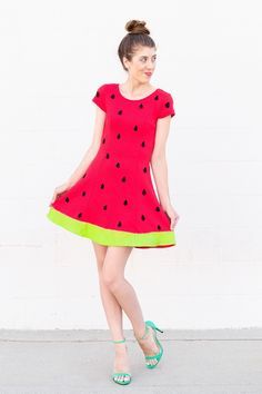 a woman wearing a red dress with black dots on it and green trim around the waist