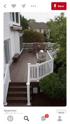 a deck with chairs, table and grill on it in front of a white house