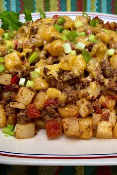 a white plate topped with potatoes covered in cheese and meat next to lettuce