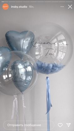 three clear balloons with blue ribbons tied to them