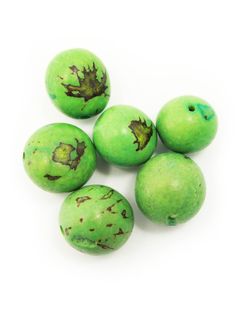 five green beads with brown spots on the top, and one has been peeled off