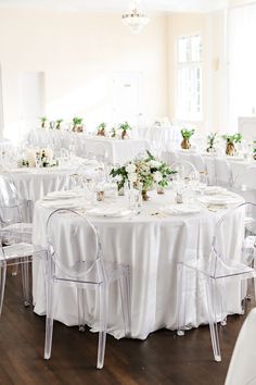 a room filled with lots of white tables and chairs