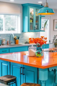 an orange and blue kitchen island with stools next to it in front of the sink