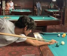 a man leaning over to hit a pool ball