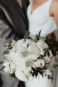 a bride and groom holding a bouquet of white flowers