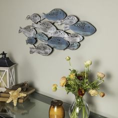 a vase filled with flowers sitting on top of a table next to a fish sculpture