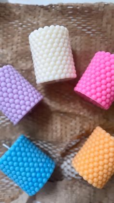 four different colored beads are arranged on a wicker mat, one is white and the other is pink